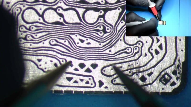 Exposed copper test pads on a monolithic microSD die under a stereomicroscope before NAND probing