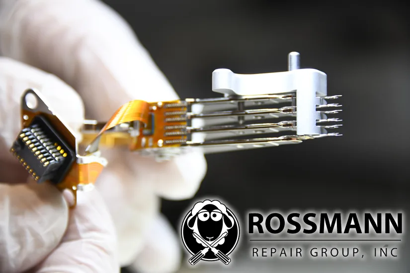 Gloved hand holding a six-slider head stack assembly with the preamp flex circuit visible, inspected before donor matching for a head swap