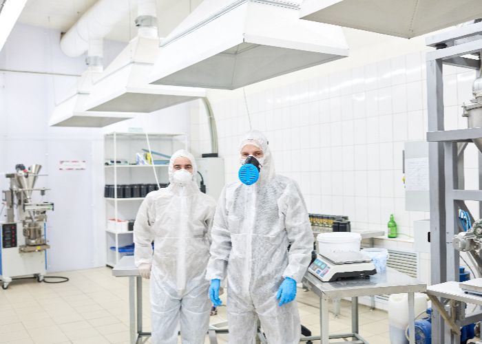 two men dressed in spacesuits in a clean room environment